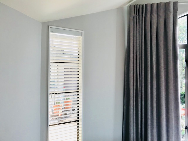 White wooden venetian blind with grey curtain