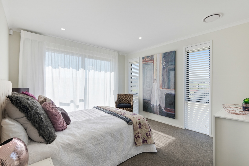 Main bedroom with sheer white drapes and wooden venetian blinds
