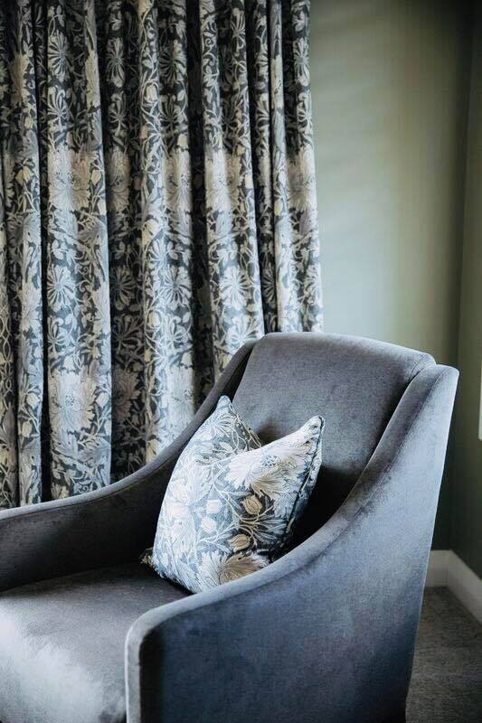 Occasional chair with floral cushion drapes behind