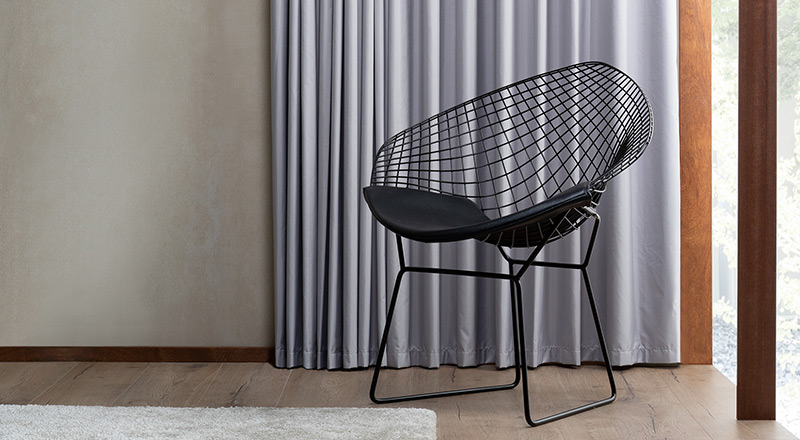 Black wire chair grey lined drapes wooden floors